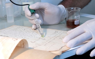 Foto de manos con guantes realizando análisis a un documento