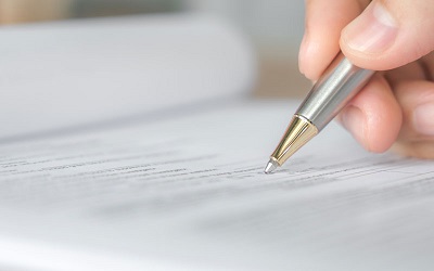 Foto de una mano sosteniendo un lapicero para firmar un documento. Enlace a Servicios notariales