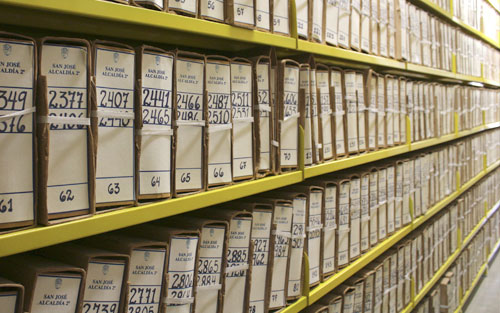 Foto de cajas de archivo numeradas, colocadas ordenadamente en estantería metálica